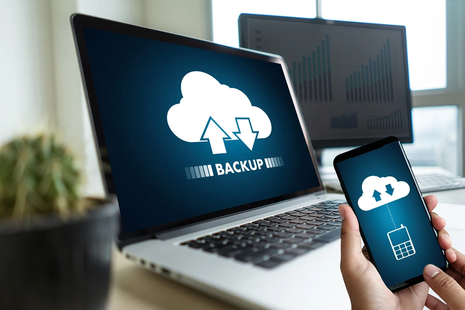 Business professional reviewing cloud backup status on a laptop and mobile device